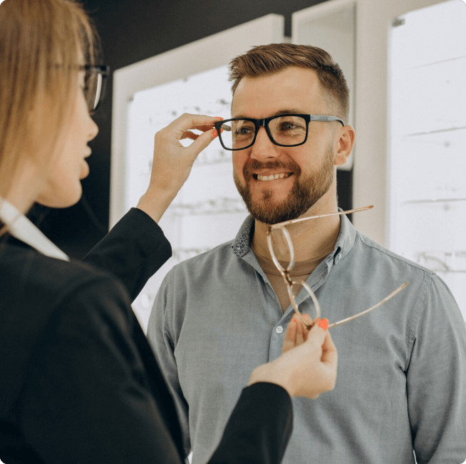 Homem experimentando óculos com auxílio de uma profissional